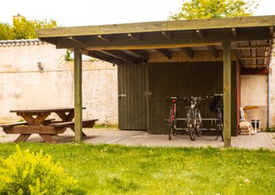 Overdækket terrasse med bord og cykler på HabitusHuset Kobberøvej.